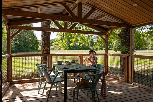 Überdachte Holzterrasse, Frau liest, Campingplatz CLICOCHIC Aloua Sevrier.