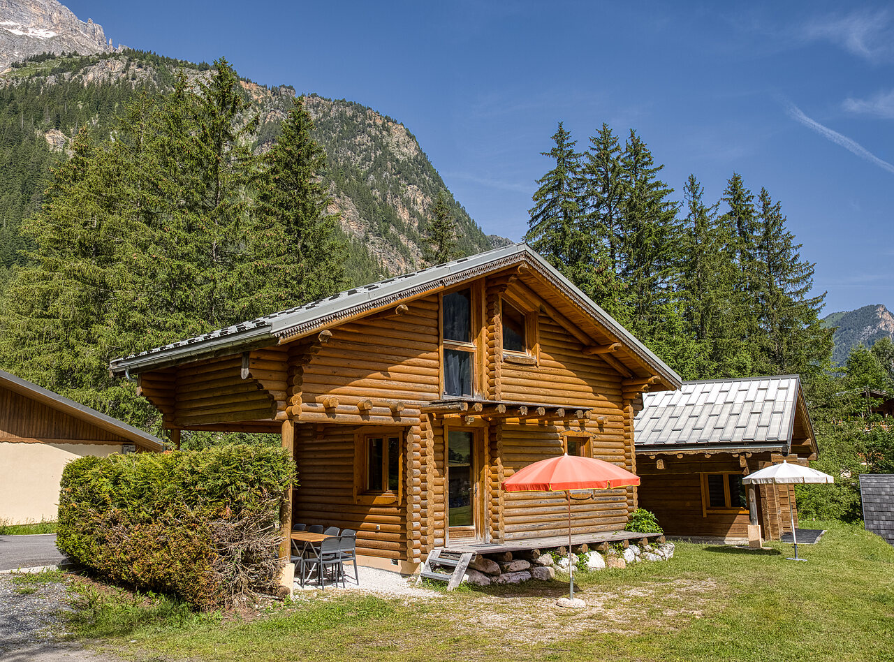 Wooden chalet with terrace and umbrella, mountains at camping CLICOCHIC Alpes Lodges in Pralognan la Vanoise (73).