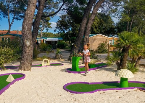 Bunte Minigolfanlage mit lächelndem Kind auf dem Campingplatz CAPFUN Arbois du Castellet in LE CASTELLET (83).