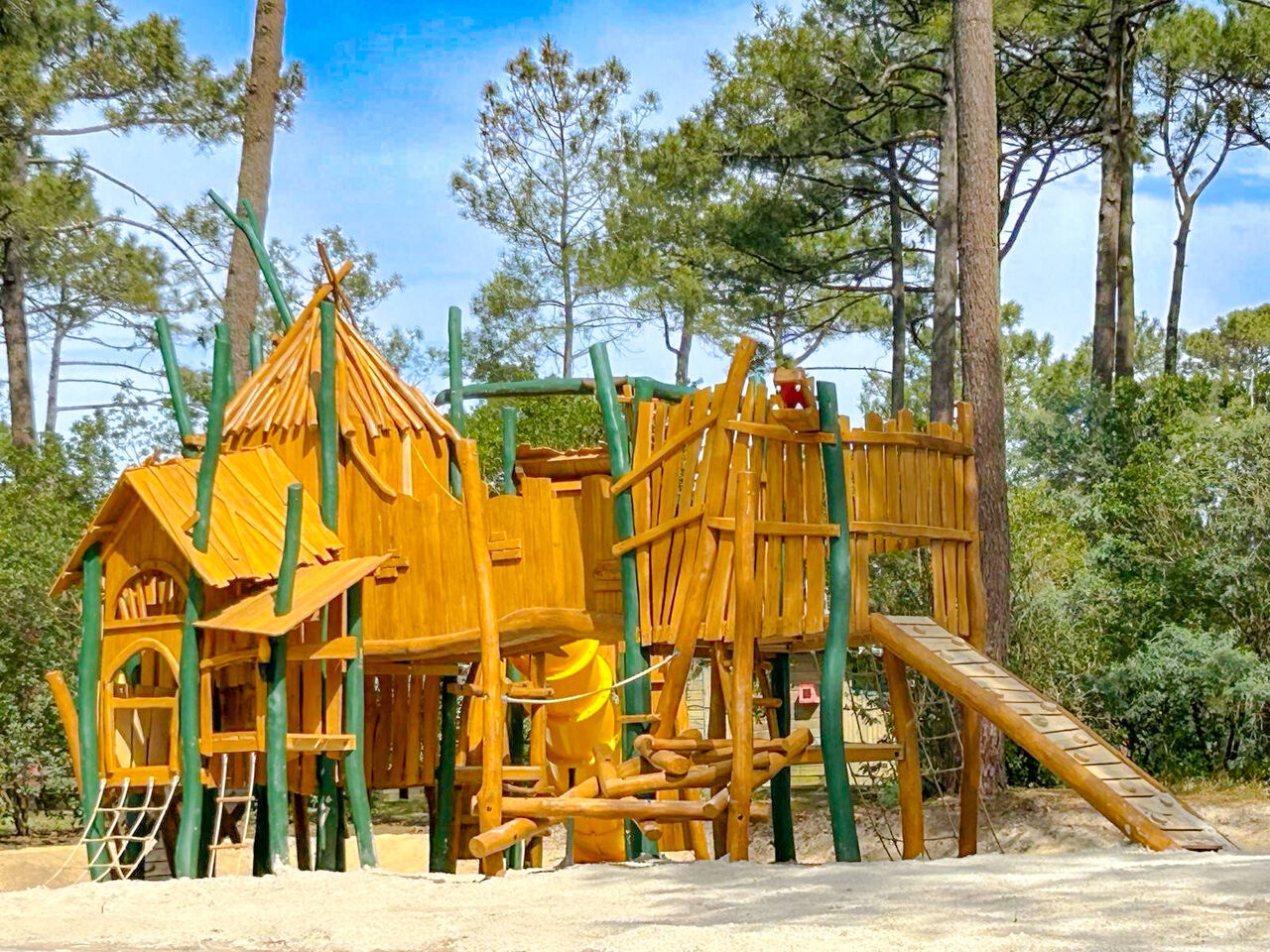 Large wooden playground structure with slide and nets at LIBRANOO Naturiste Arnaoutchot campsite in Veille-Saint-Girons, Landes, France.