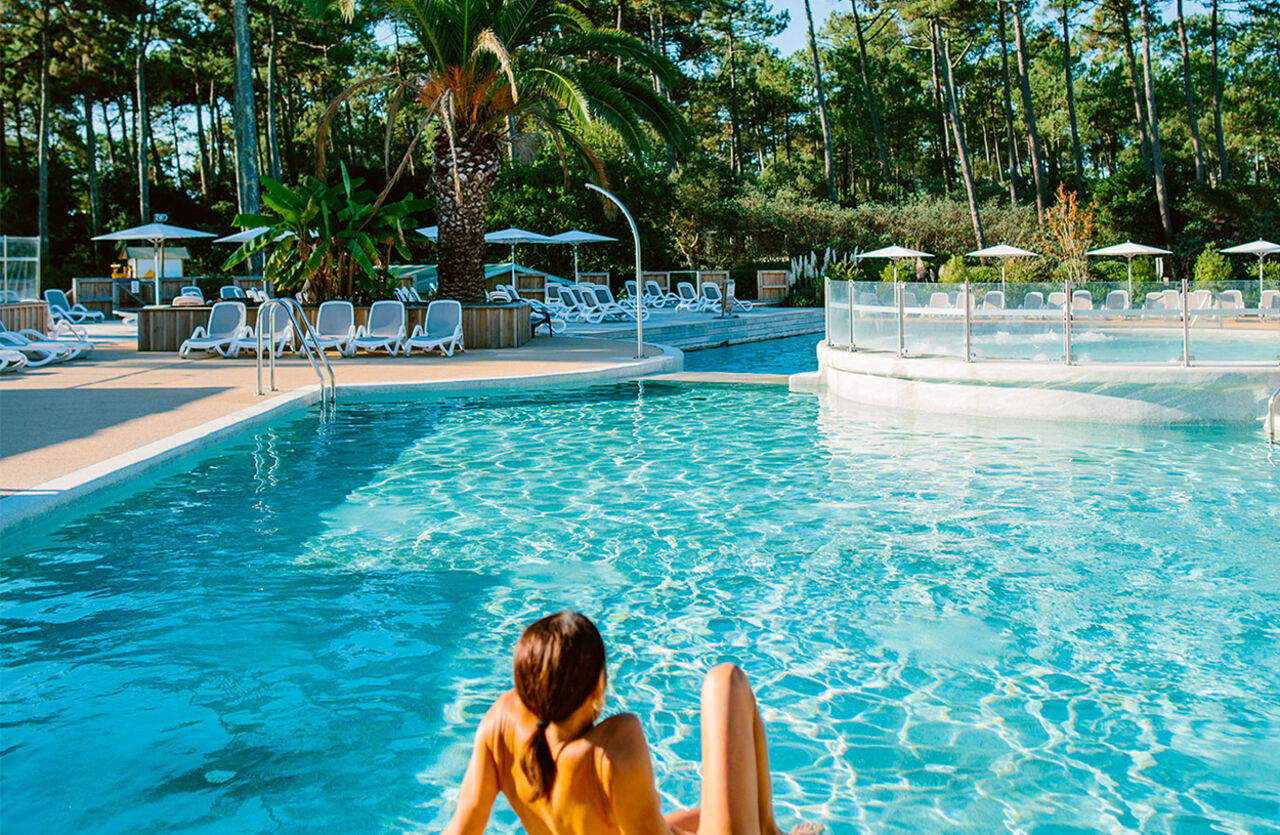 Large outdoor swimming pool with sun loungers and lush vegetation at LIBRANOO Naturiste Arnaoutchot campsite in Veille-Saint-Girons, Landes, France. (40).