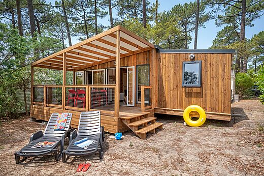 Modernes Holz-Mobilheim mit überdachter Terrasse auf dem Campingplatz LIBRANOO Naturiste Arnaoutchot in Veille-Saint-Girons, Landes, Frankreich.