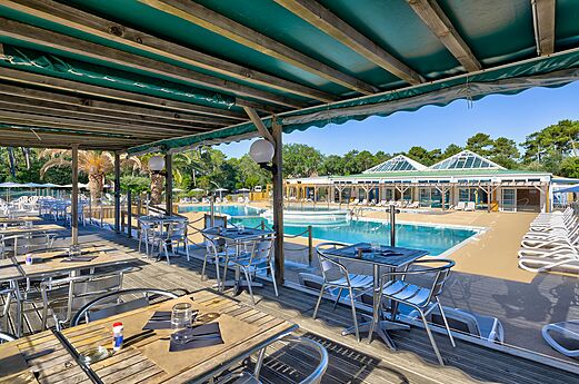 Terrasrestaurant en buitenzwembad op camping LIBRANOO Naturiste Arnaoutchot in Veille-Saint-Girons, Landes, Frankrijk.