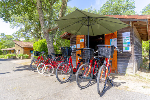 Rote Fahrräder zum Mieten vor der Verleihstation auf dem Campingplatz LIBRANOO Naturiste Arnaoutchot in Veille-Saint-Girons, Landes, Frankreich.