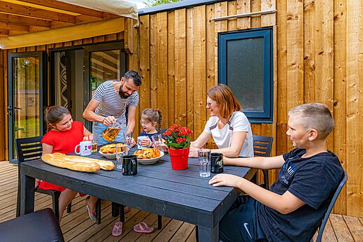 Familie isst auf Terrasse Mobil-home auf Camping CAPFUN Aube in Deltebre, Tarragona.