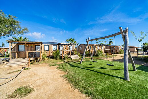 Wooden mobile homes with swings at CAPFUN Aube campsite in Deltebre, Tarragona.