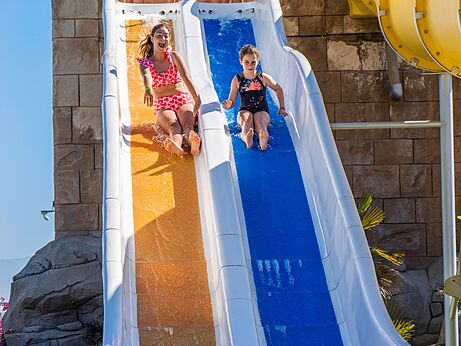 Kinder rutschen bunte Wasserrutsche hinunter auf Camping CAPFUN Aube in Deltebre, Tarragona.