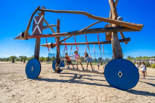 Einzigartiger Holzspielplatz mit Kindern auf Seilbrücke auf dem Campingplatz CAPFUN Aube in Deltebre, Tarragona.