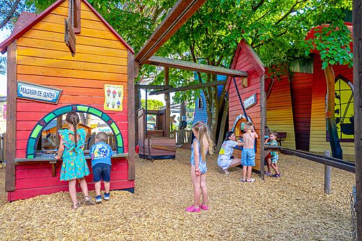 Aire de jeux colorée avec cabanes et enfants au camping CAPFUN Aubrèdes à Puget sur Argens (83).