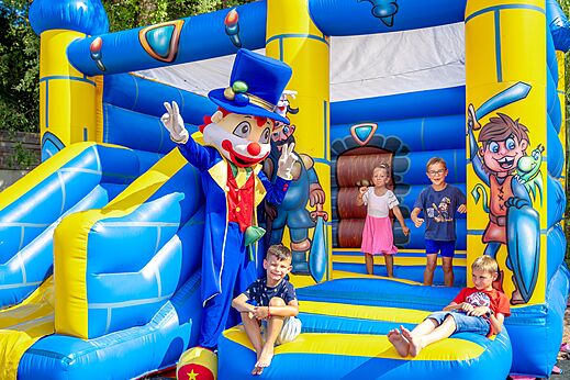 Enfants sur jeux gonflables avec mascotte au camping CAPFUN Aubrèdes à Puget sur Argens (83).