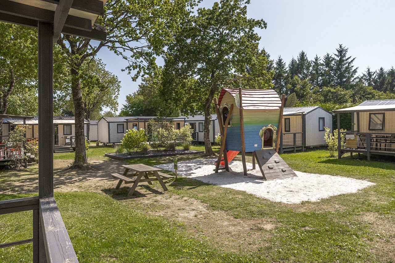 Kinderspielplatz, Spielhaus, Rutsche und Mobilheime auf dem Campingplatz CLICOCHIC in Poullan-sur-Mer.