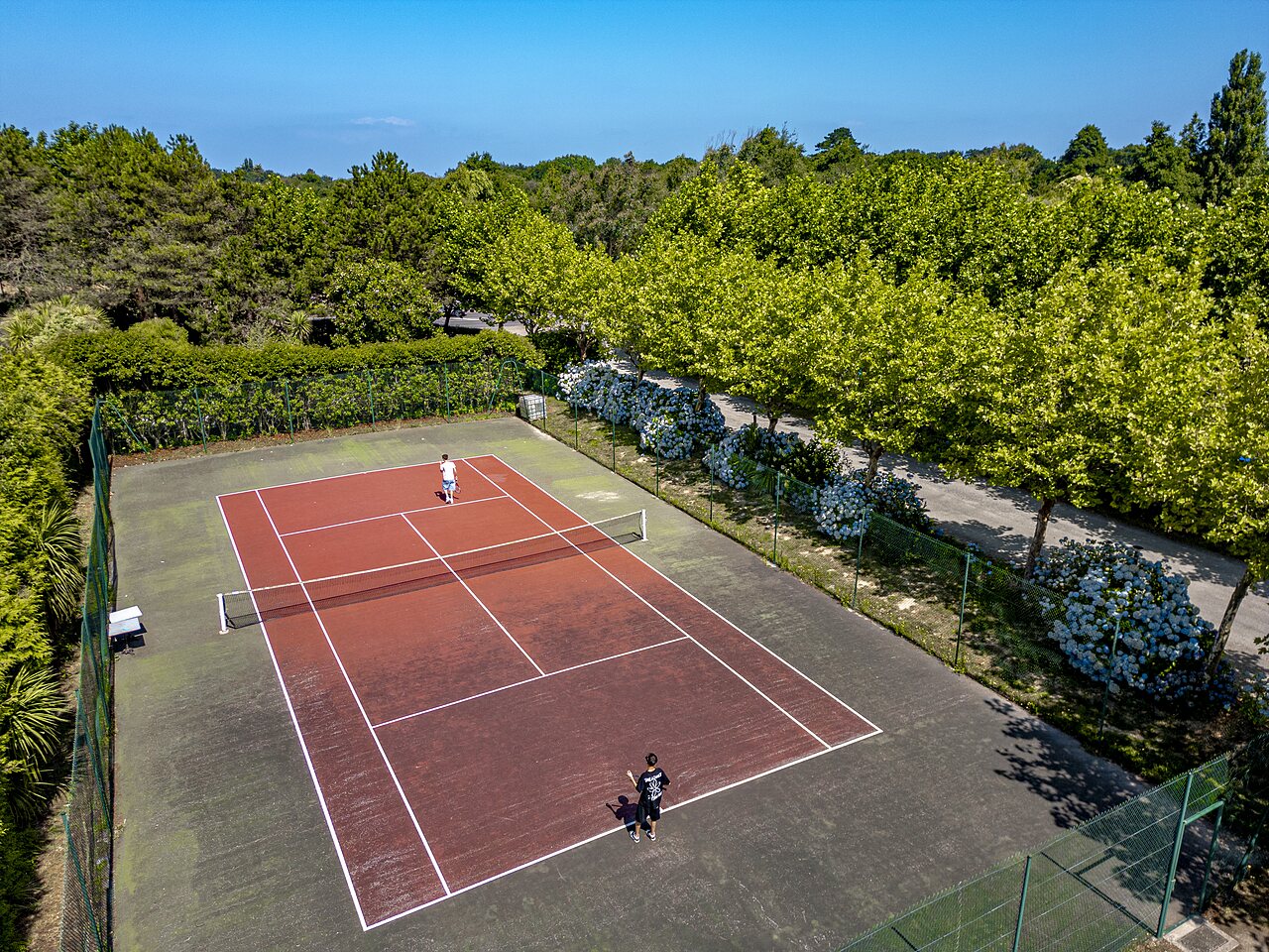 Au�en-Tennisplatz mit Spielern auf dem Campingplatz CLICOCHIC Baie de Douarnenez (29).
