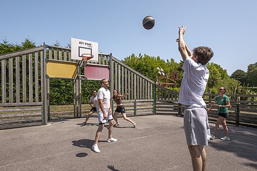 Multisportplatz mit Urlaubern beim Basketballspielen auf dem Campingplatz CLICOCHIC Baie de Douarnenez in Poullan-sur-Mer.
