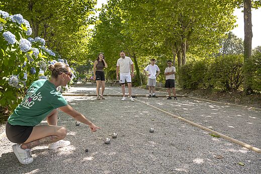 Schattiger Bouleplatz mit Spielern auf Camping CLICOCHIC Baie de Douarnenez in Poullan-sur-Mer.