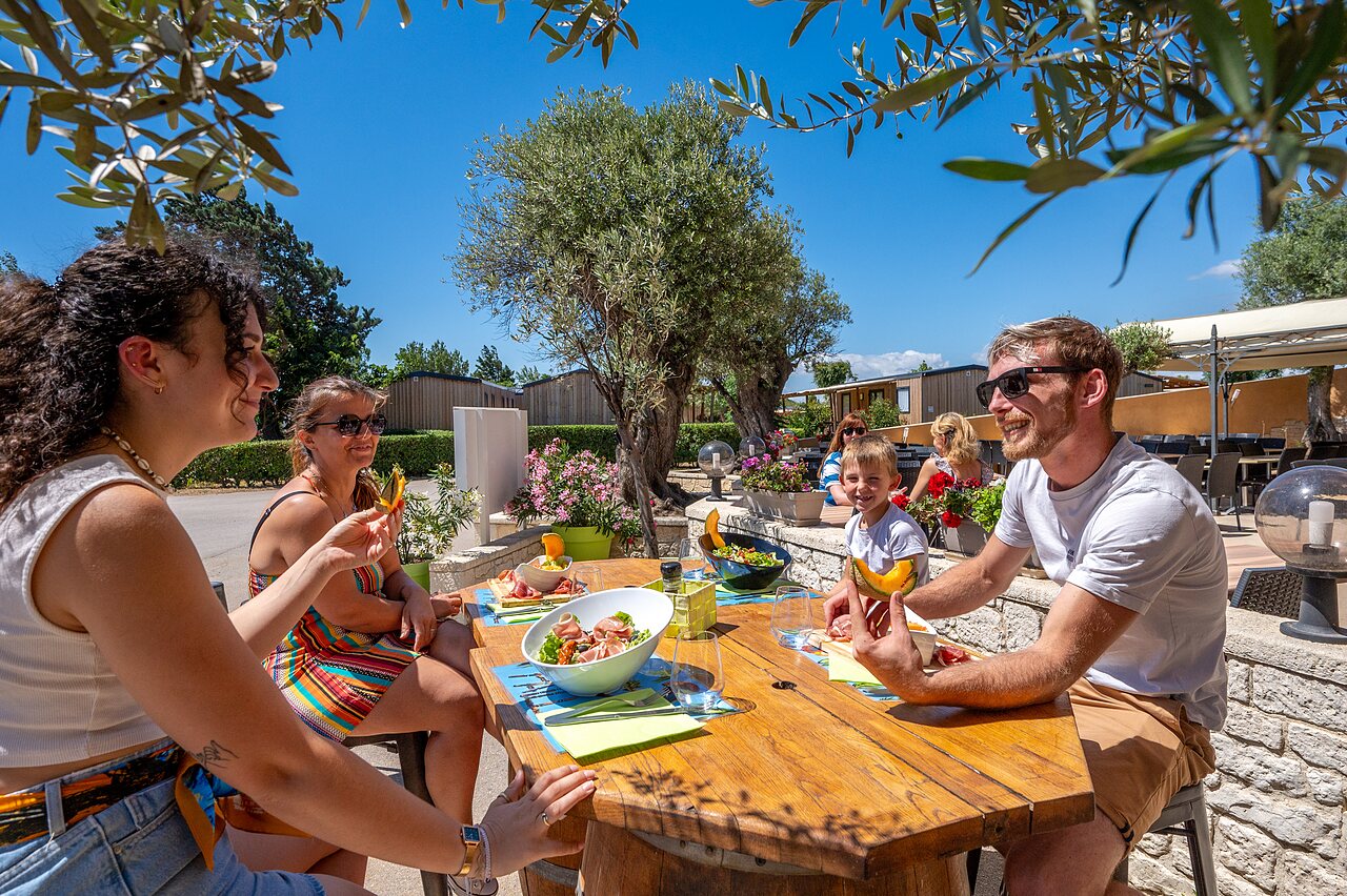 Famille souriante d�jeunant en terrasse ombrag�e, mobile homes au camping CAPFUN Barbacane � NARBONNE (11).