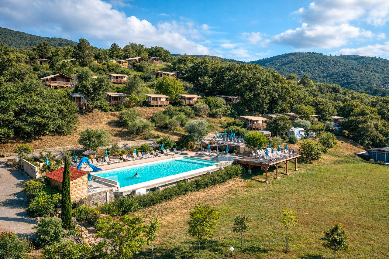 Outdoor pool, slide, and chalets at CLICOCHIC Bastets campsite in Marsanne (26).