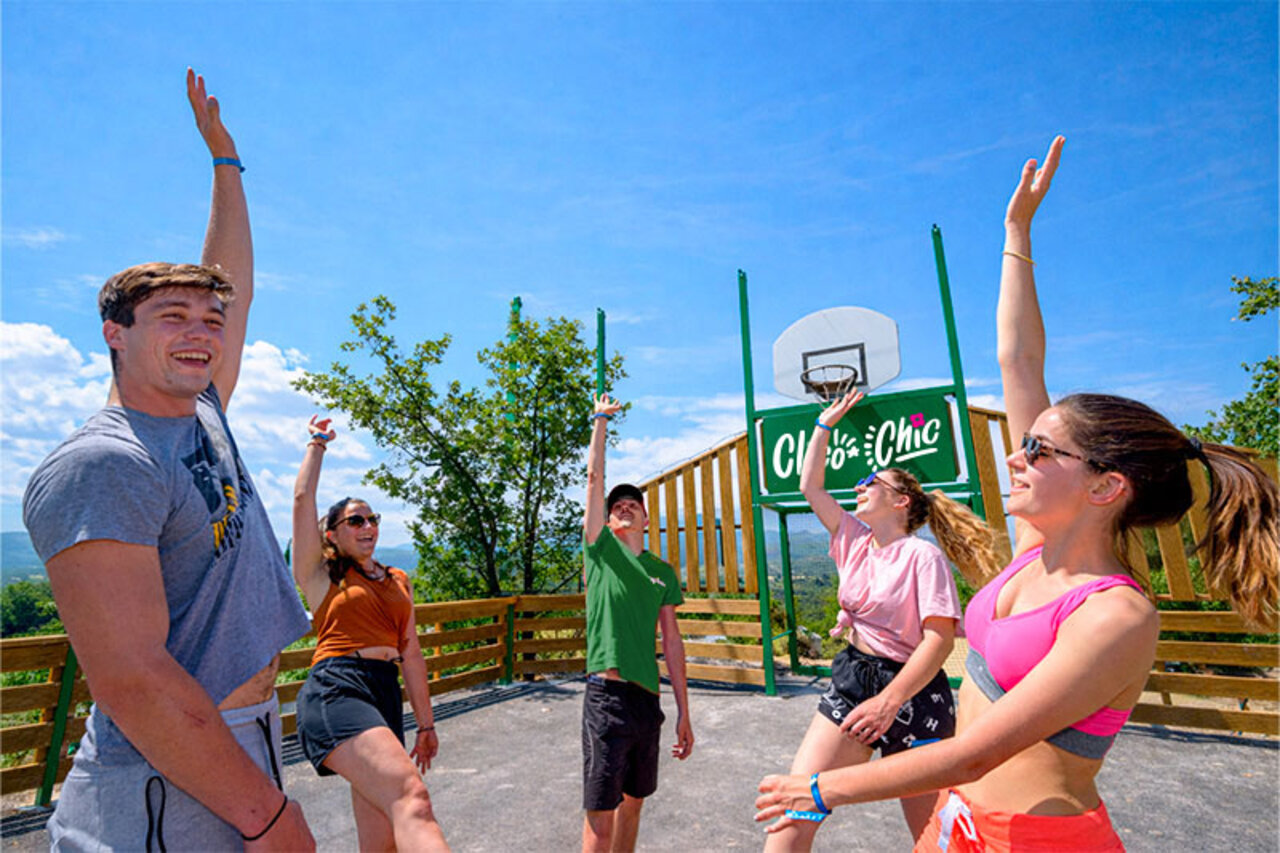 Young people playing basketball on multisport court at CLICOCHIC Bastets campsite in Marsanne (26).