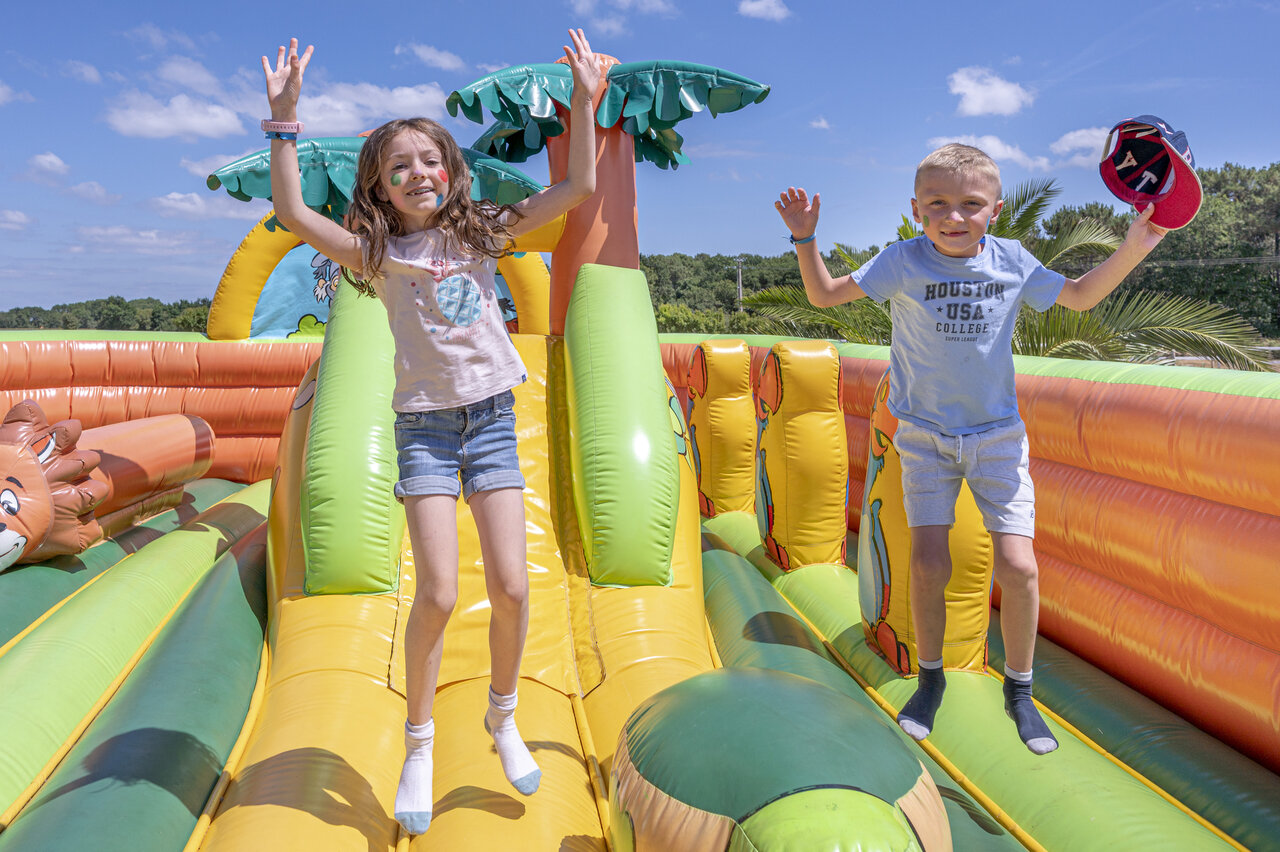 Children jumping on tropical bouncy castle at CLICOCHIC Bastets campsite in Marsanne (26).