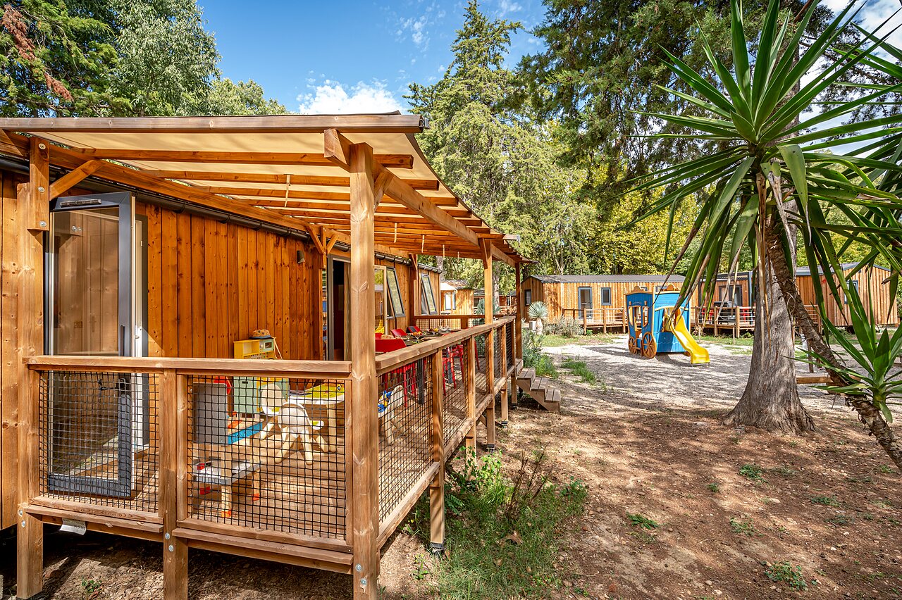 Holz-Mobilheim mit �berdachter Terrasse und Spielplatz auf Camping CAPFUN Bastide in N�mes (30).