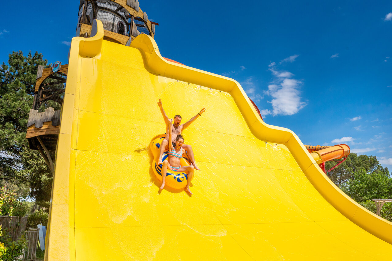 Couple enjoying giant water slide at CAPFUN Beauregard campsite in MORNAS (84).