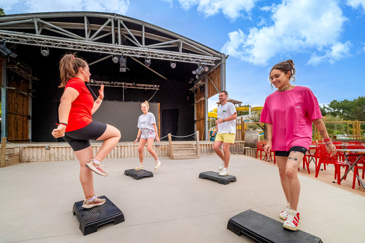Step aerobics class on outdoor stage at CAPFUN Beauregard campsite in MORNAS (84).