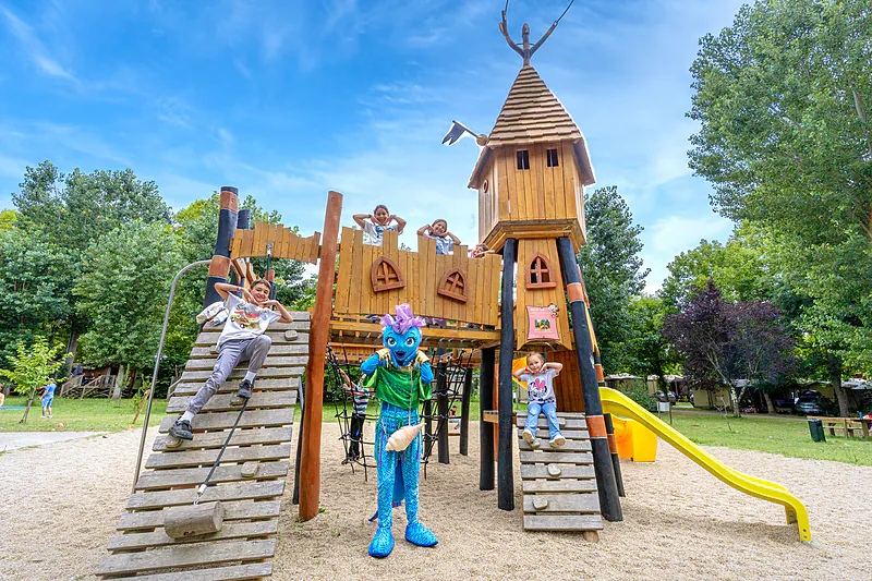 Wooden playground, children and mascot at CLICOCHIC Beau Rivage campsite in LA ROQUE-GAGEAC (24).