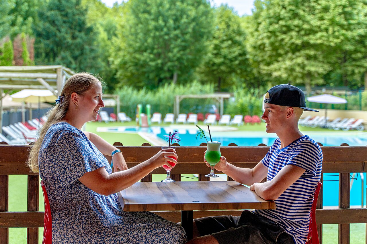 Couple enjoying cocktails at the bar, pool, at CLICOCHIC Beau Rivage campsite in LA ROQUE-GAGEAC (24).