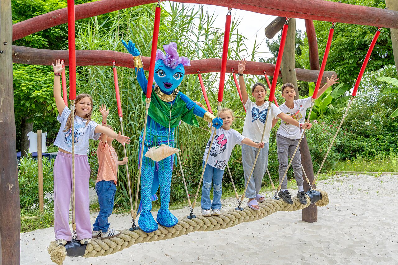 Children and mascot on rope bridge, playground at CLICOCHIC Beau Rivage campsite in LA ROQUE-GAGEAC (24).