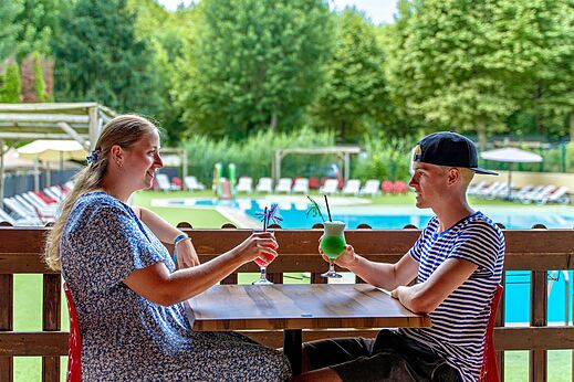 Lächelndes Paar mit Cocktails an der Poolbar, auf dem Campingplatz CLICOCHIC Beau Rivage in LA ROQUE-GAGEAC (24).