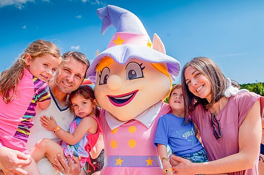 Maskottchen und lächelnde Familie auf dem Campingplatz CAPFUN Bel Air in Aiguillon sur Mer (85).