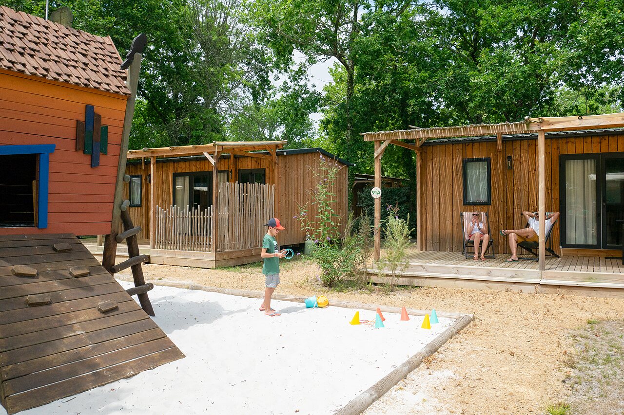 Wooden mobile homes, play area, family at CLICOCHIC Bimbo campsite in BISCARROSSE (40).