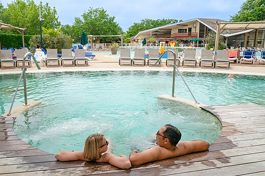 Paar entspannt im Whirlpool am Pool auf Campingplatz CLICOCHIC Bimbo in BISCARROSSE (40).