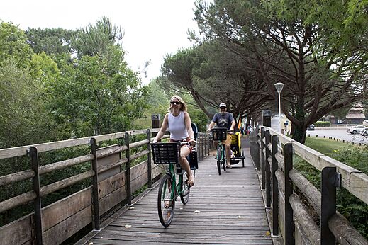 Familie fährt Fahrrad auf Holz-Radweg am Campingplatz CLICOCHIC Bimbo in BISCARROSSE (40).