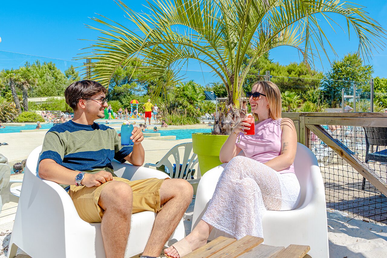 Paar mit Cocktails am Pool auf dem Campingplatz VAGUES OCEANES Blancs Ch�nes in LA TRANCHE SUR MER.
