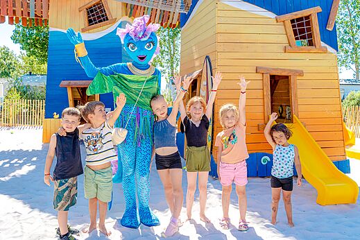 Maskottchen und Kinder auf dem Spielplatz des Campingplatzes VAGUES OCEANES Blancs Ch�nes.