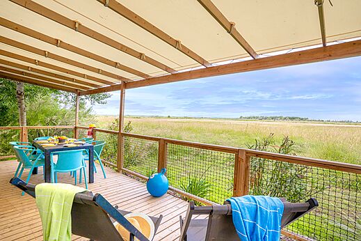 �berdachte Unterkunftsterrasse mit Esstisch und Naturblick auf dem Campingplatz VAGUES OCEANES Blancs Ch�nes in LA TRANCHE SUR MER (85).