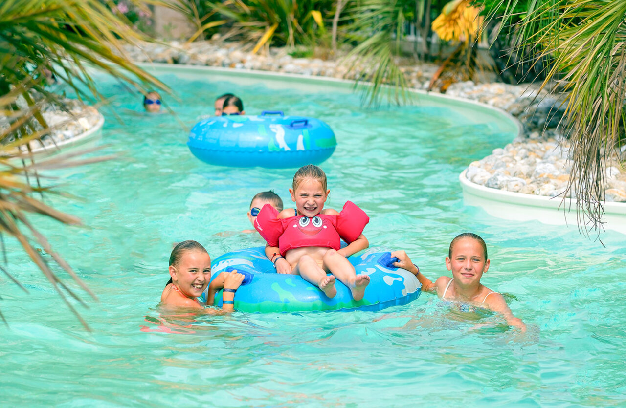 L�chelnde Kinder auf Schwimmreifen im Pool-Fluss VAGUES OCEANES Bois Joly.