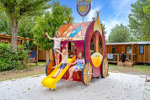 Originele speeltuin in koetsvorm met kinderen op camping VAGUES OCEANES Bois Joly.