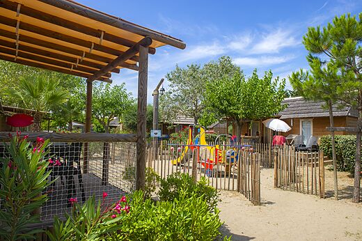 Colorful playground and wooden Mobil-homes at CAPFUN Boucanet campsite in LE GRAU DU ROI (30).