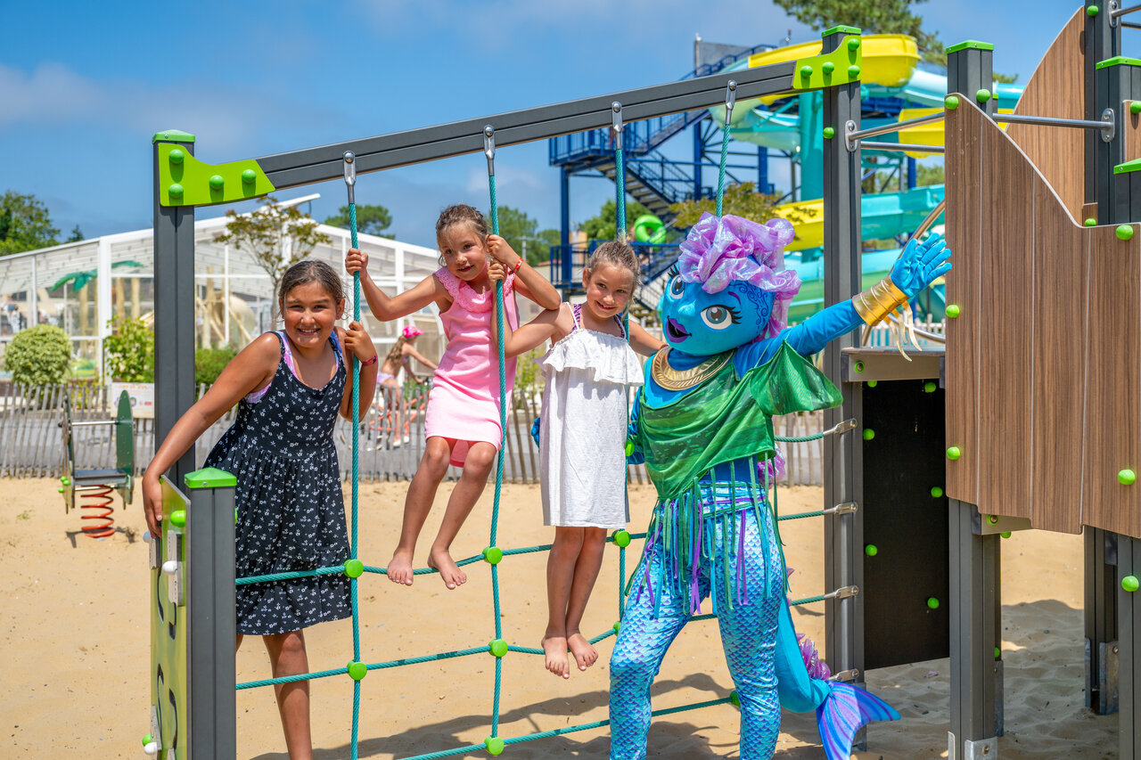 Children and mascot on playground, water slides at VAGUES OCEANES Boudigau campsite.