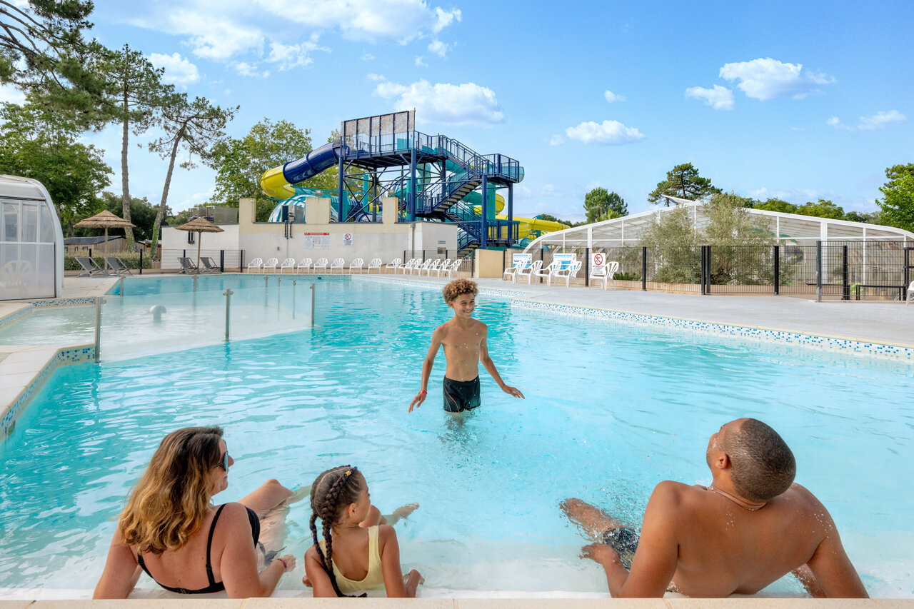 Family enjoying the outdoor swimming pool with water slides at VAGUES OCEANES Boudigau campsite in LABENNE OCEAN (40).