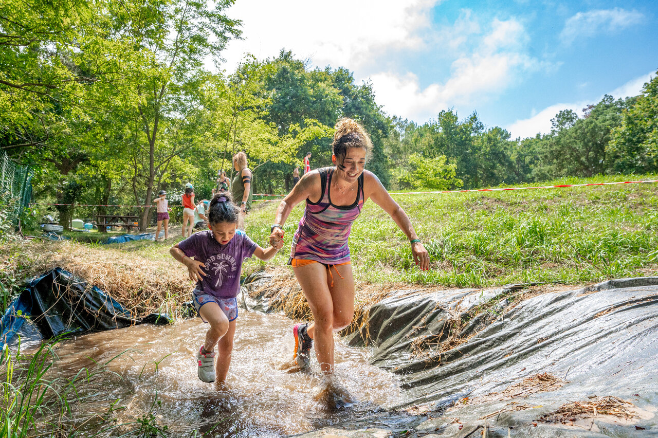 Mother and child smiling in muddy obstacle race at camping VAGUES OCEANES Boudigau in LABENNE OCEAN (40).