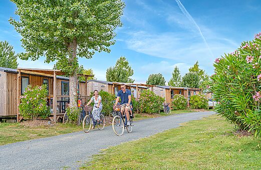 Fahrradtour vor Holz-Mobilheimen auf dem Campingplatz CLICOCHIC Brandais.