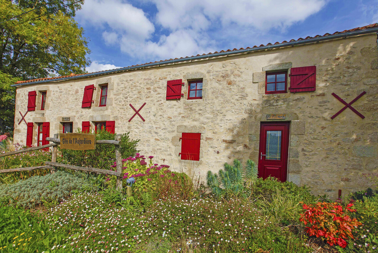 Stein-G�te, rote Fensterl�den, bl�hender Garten auf Camping CAPFUN Breteche, Les Epesses.