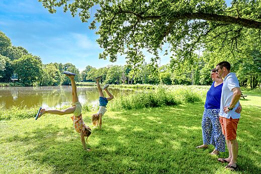 Kinder machen Handstände am See, Erwachsene schauen zu auf Camping CAPFUN Breteche (85).