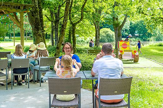 Familie isst auf Außenterrasse, Kinderspielplatz, Camping CAPFUN Breteche in Les Epesses (85).