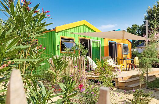 Colorful mobile home with wooden deck and outdoor furniture at CLICOCHIC Cabanes d Oléron campsite in ST GEORGES D'OLERON (17)
