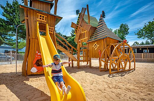Child on slide, wooden playground at camping CLICOCHIC Cabanes d Oléron in ST GEORGES D'OLERON (17).