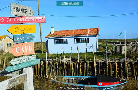 Farbenfroher Wegweiser und typisches Haus am Wasser in Ch�teau d'Ol�ron.