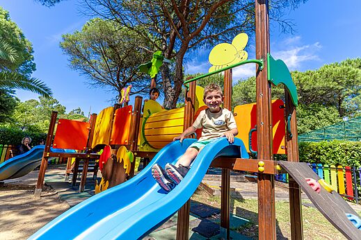 Smiling child on a colorful slide in the playground at CAPFUN Campo dei Fiori campsite in Rosignano Marittimo (57).